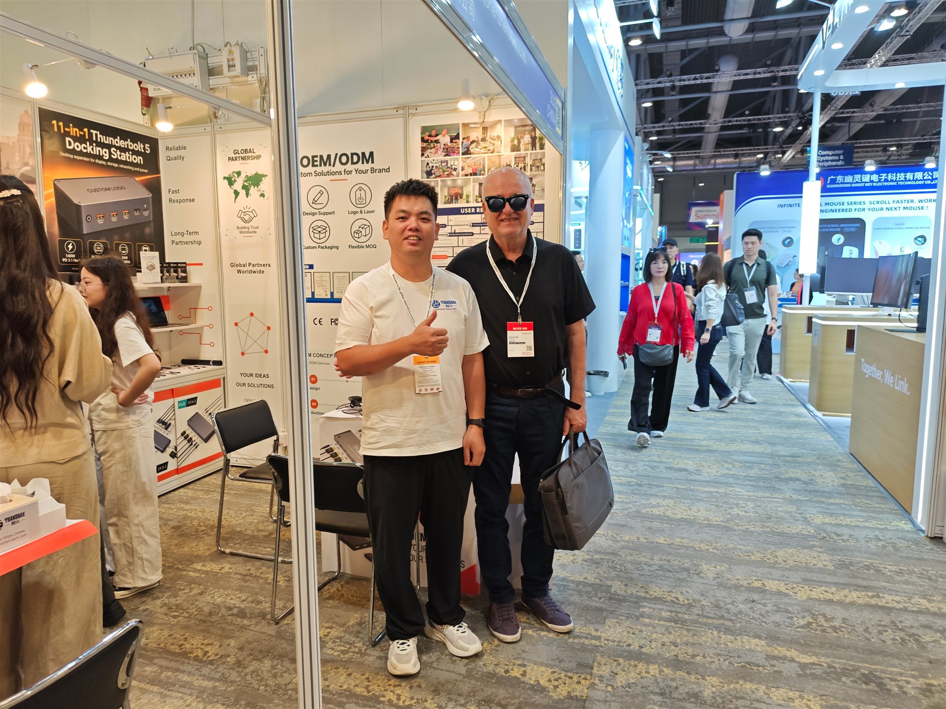 A visitor and a Yuanshan team member posing for a photo at the exhibition booth