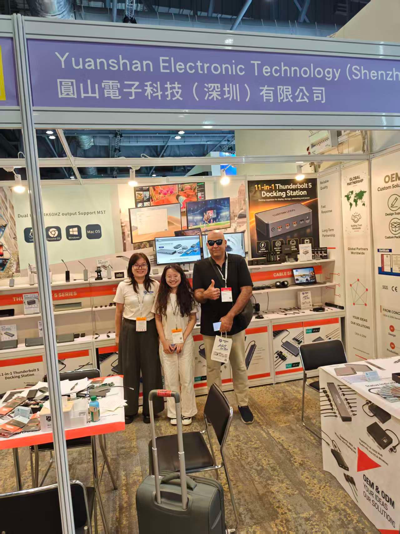 A group posing for a photo in front of the Yuanshan product display and company sign